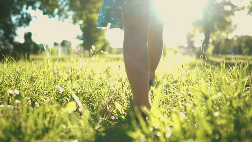 A child walks on the grass. concept of happy childhood and loving family for a kid. a little child walks on green grass in a park, legs close-up, sun glare on the lifestyle background | Shutterstock HD Video #1112020481