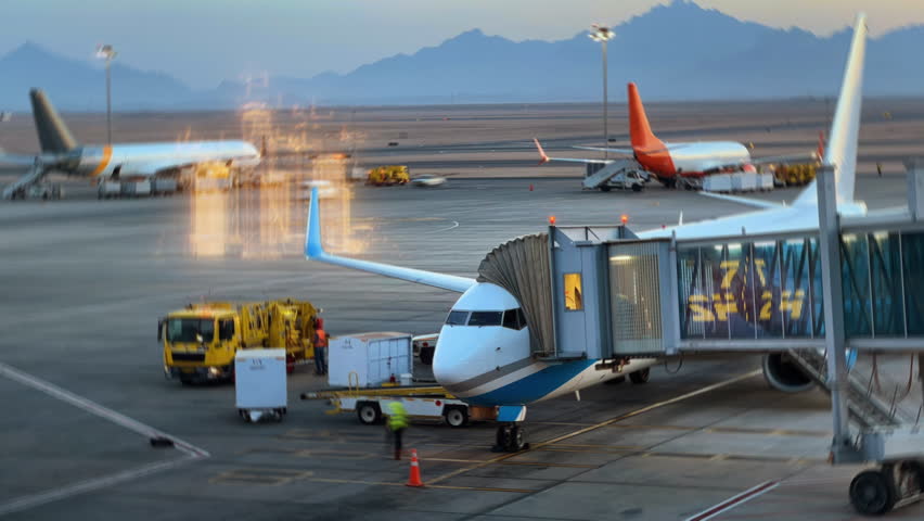 Time Lapse vehicles and workers refilling, loading cargo in to airplane at the airport with holographic city. Logistic transportation