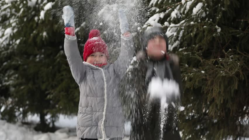 Happy kids girl and boy playing outdoor in snowy winter forest and throwing snow. Active winter holidays celebrate concept. Happy childhood