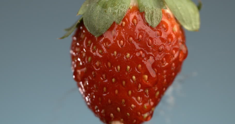 Super slow motion macro of splashing clear pure water drops are falling on fresh ripe bio organic red strawberry fruit isolated on soft warm background.  Royalty-Free Stock Footage #1112032655