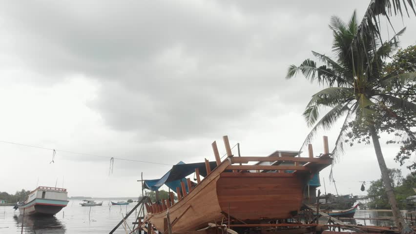 Flying backwards at local boat construction site at Indonesia, aerial
