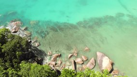 Drone footage of granite stones near the beach, surrounded by trees, turquoise water, anse Louis, Mahe Seychelles 30 fps