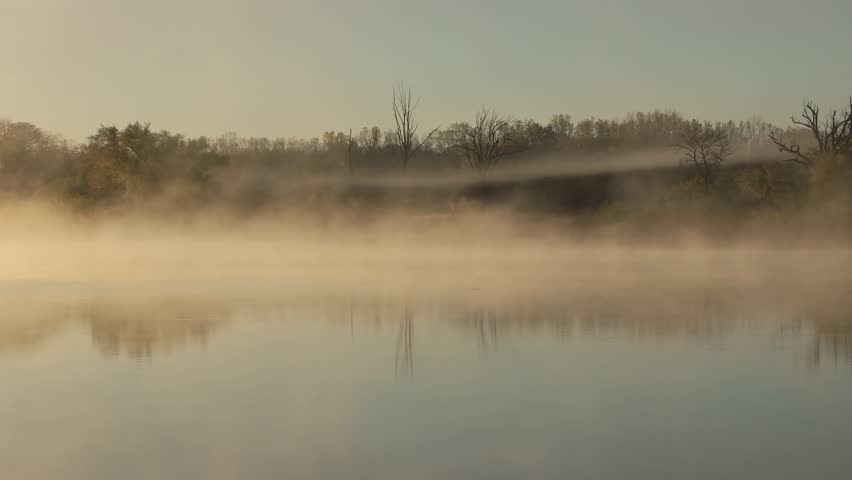 Morning fog moving over a calm lake