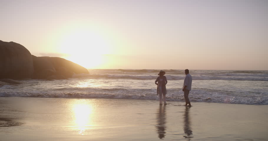 Mature couple, walking on beach and hand holding in sunset and married on holiday, outdoor and happy. Retirement, elderly or love for commitment, bonding together or care for romantic relationship