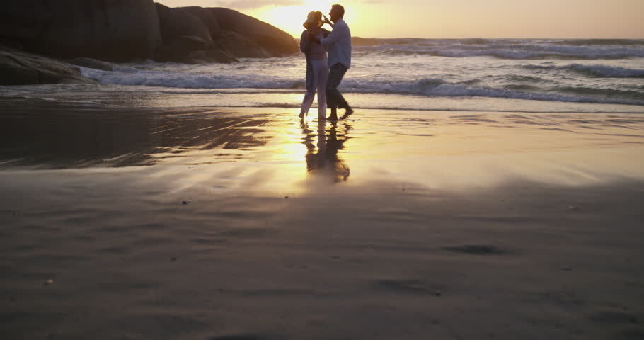 Happy couple, dancing on beach and playful in sunset and married on holiday, outdoor and retired. Retirement, elderly or love for commitment, bonding together or care for romantic relationship