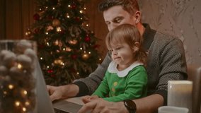 Father trying to work from home on Christmas Eve and his toddler doesn't let him, a funny child in an elf costume typing on a keyboard.