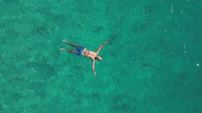 Aerial view of young man relaxing in the sea. Man enjoys turquoise sea lying on back - Powered by Shutterstock - Get 15% off with code: PIKWIZARD15