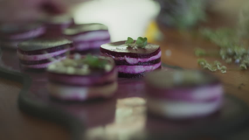 Chef placing edible flowers on a gourmet dish with tweezers. Slow motion, shallow depth of field.
