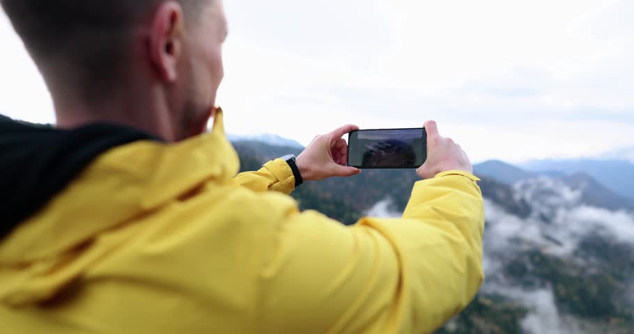 Male traveler taking pictures on mobile phone mountains 4k movie slow motion. Hobby photographing nature concept