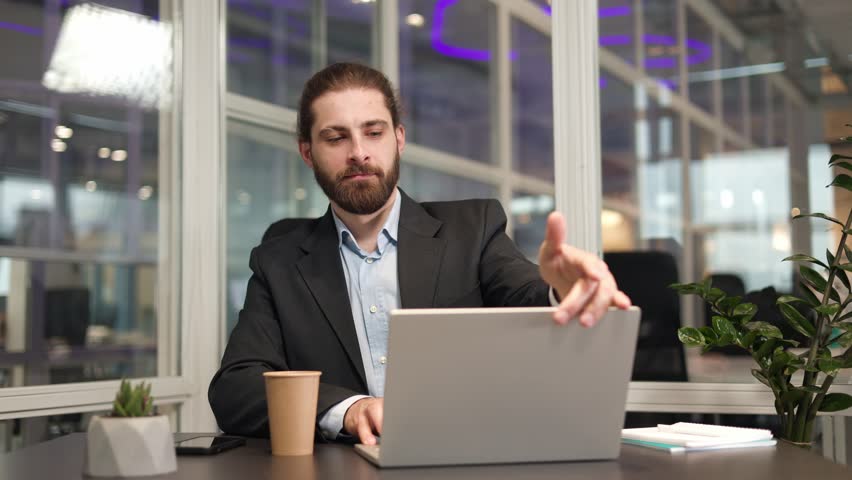 Glad office employee closing his portable computer while sitting at desk in evening. Smiling formally dressed professional feeling relaxed after long hours of productive work with modern gadget. | Shutterstock HD Video #1112053065