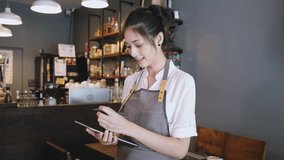 Beautiful Barista Entrepreneur Asian woman standing in cafe and using digital tablet while receive order online, looking at camera. Startup small business owner, SME business delivery online concept. - Powered by Shutterstock - Get 15% off with code: PIKWIZARD15
