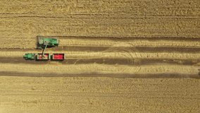 Above top view, drone is follow harvester, combine as harvest mature wheat and unloading in motion. Tractor with two trailers driving parallel in transshipment - Powered by Shutterstock - Get 15% off with code: PIKWIZARD15