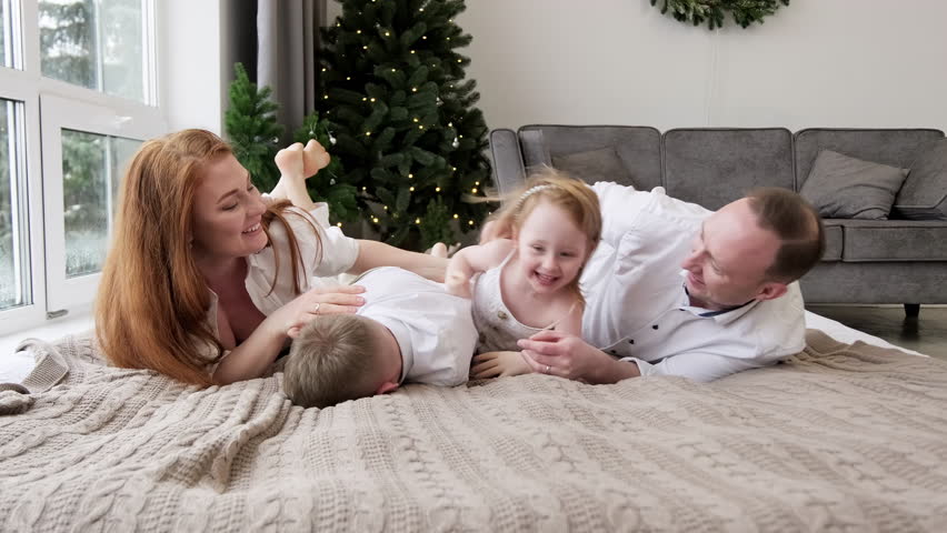 Mother and father celebrating festive holiday with kids. Christmas morning. Happy family hugging on bed. Christmas holidays concept. 4K, UHD | Shutterstock HD Video #1112057351