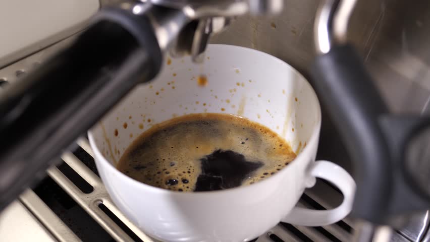 Close-up flowing fresh ground coffee. Pour coffee stream from the professional machine into the cup. Barista making double espresso with grinder oder filter holder. Drink a roasted black coffee  | Shutterstock HD Video #1112057573