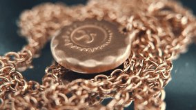A detailed crispy macro shot of a golden medallion necklace, flying bird in the middle of the sun symbol, on a rotating stand, mirror reflection, studio lighting, 4K video