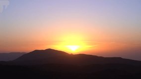 Stunning Aerial Timelapse of a Radiant Sunset Behind Majestic Mountains 4K Breathtaking Sky Colors and Serene Mountain Silhouettes