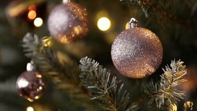 Shiny powder pink ball hanging on Christmas tree against festive lights. Space for text - Powered by Shutterstock - Get 15% off with code: PIKWIZARD15