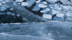 Video of winter ice texture of frozen Baikal Lake in cold February day. Natural seasonal background with blue ice cover with white bubbles and big cracks. Close-up, top view - Powered by Shutterstock - Get 15% off with code: PIKWIZARD15