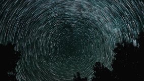 Time lapse of comet-shaped star trails over the forest in the night sky. Stars move around a polar star. 4K - Powered by Shutterstock - Get 15% off with code: PIKWIZARD15