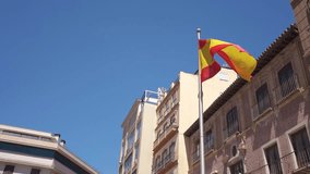 Slow motion video with the Spanish flag moving in the wind. Clear blue sky. City center of Malaga. 