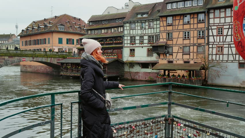 Front view portrait of confident Caucasian calm woman standing on river bridge. Female smiling on camera while travelling.