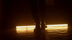 Silhouette of feet in winter boots walking along a dark corridor. Orange light. - Powered by Shutterstock - Get 15% off with code: PIKWIZARD15