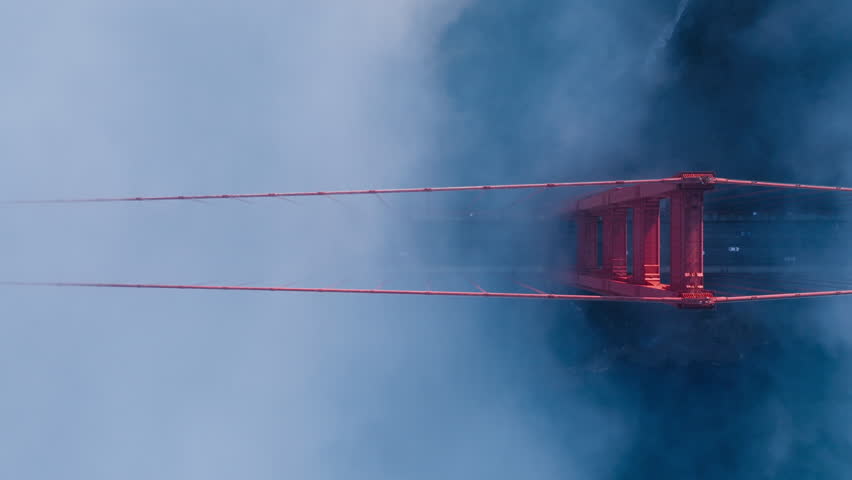 Top down aerial of cars driving by red Golden Gate Bridge. B roll American landmark USA 4K. Establishing shot dramatic deep blue purple fog cloud flying around red Golden Gate bridge in San Francisco