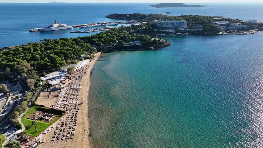 Aerial drone video from famous celebrity sandy beach of Astir or Asteras in south Athens riviera with turquoise clear sea, Vouliagmeni, Greece