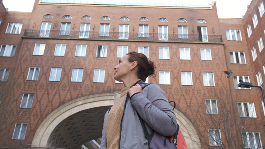 Female walk against sightseeing facade. A female with interest look around the brick houses in the Europe city during day time.