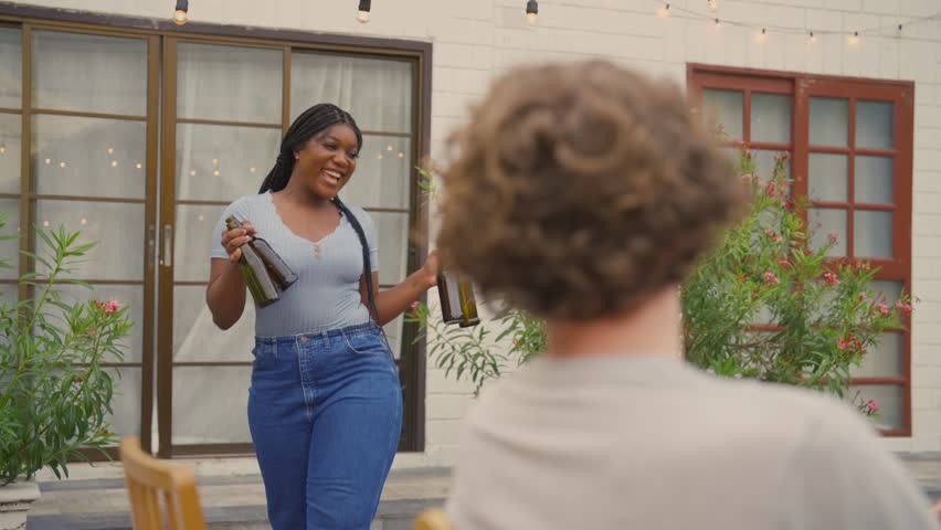 Multi-ethnic family having fun, enjoy party outdoors in the garden. Attractive diverse group of people having dinner, eating foods, celebrate weekend reunion gathered together at the dining table.