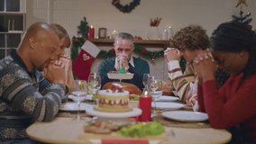 Multi-ethnic big family saying a prayer before having Christmas dinner. Attractive diverse group of people having dinner eating food to celebrate holiday Thanksgiving X-mas eve on dining table at home - Powered by Shutterstock - Get 15% off with code: PIKWIZARD15