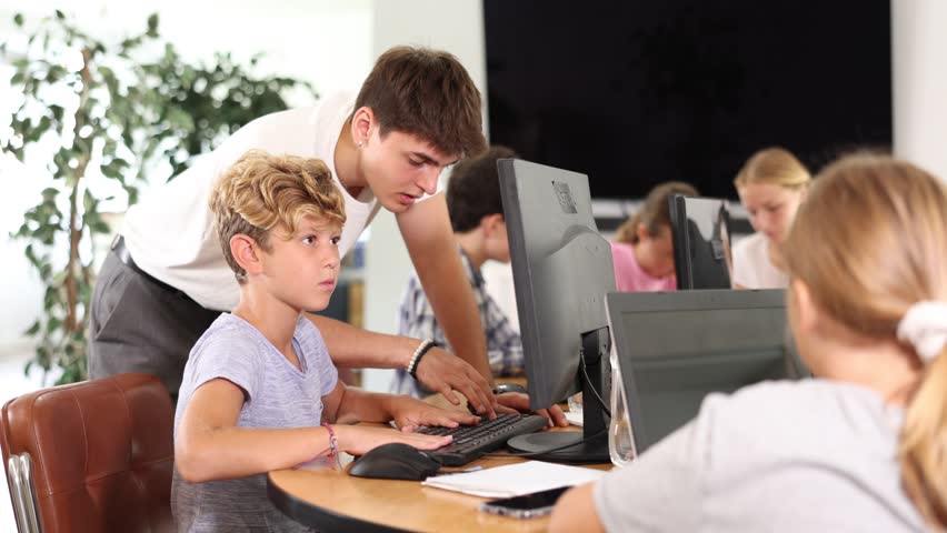 Concerned preteen boy sitting at computer while trainer explaining him something during IT courses  Royalty-Free Stock Footage #1112081805