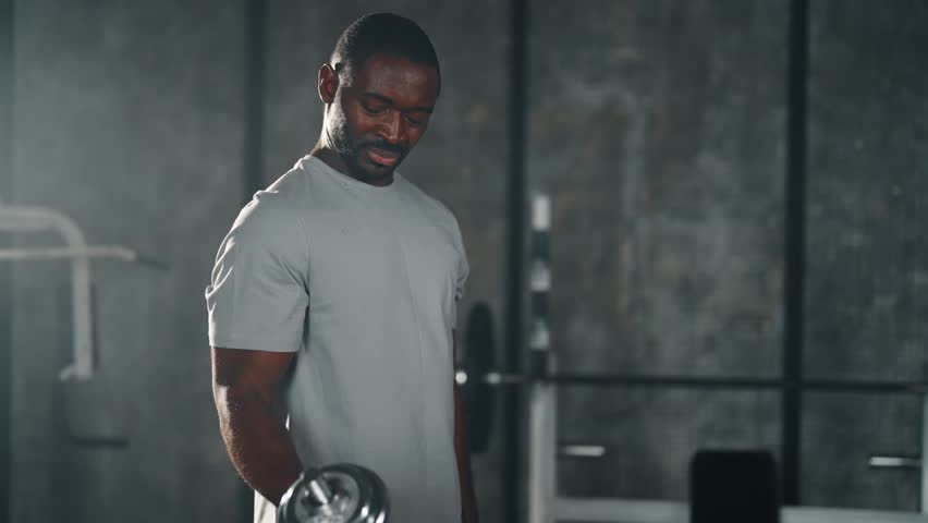 African american man lifts dumbbells. Sportive strong bearded guy has intensive strength power hands training exercising biceps in gym. Workout, sport healthy lifestyle, making athletic body concept. | Shutterstock HD Video #1112086873
