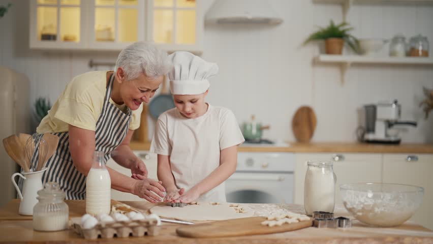 Happy granny granddaughter cook at home. Family senior grandmother teaching child girl baking cookies clapping hands laughing together on kitchen. Cooking culinary, bakery preparing food bake concept. | Shutterstock HD Video #1112086927