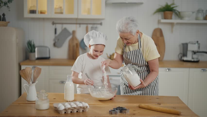 Grandma granddaughter cooking at home. Grandmother teaching child girl kneading dough on table explaining process baking together on kitchen. Cook culinary cuisine bakery preparing food bake concept. | Shutterstock HD Video #1112086931