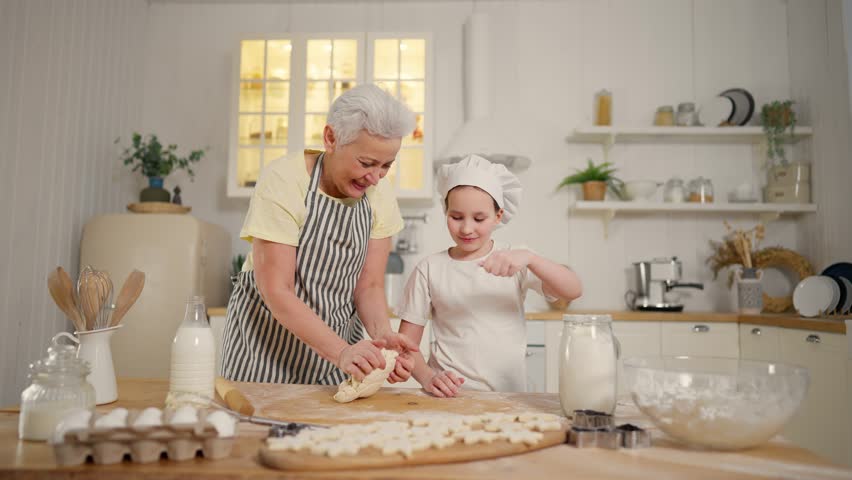 Grandma granddaughter cooking at home. Family senior grandmother teaching child girl baking making dough sprinkling flour together on kitchen. Cook culinary cuisine bakery preparing food bake concept. | Shutterstock HD Video #1112086933