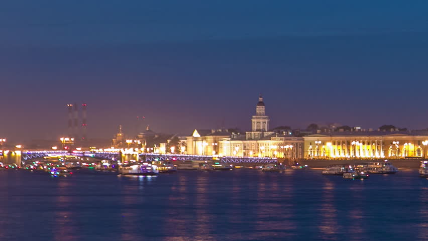 Timelapse of Palace Bridge opening and the iconic Spit of Vasilyevsky Island with the Old Stock Exchange. Numerous observing tourists, ships, and boats grace the Neva River at night. Saint-Petersburg