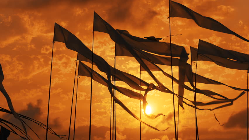 Silhouettes of decorative flags are fluttering in the wind against the dramatic sunset orange sky at the outdoor city festival. Freedom, entertainment, summer and celebration concept Royalty-Free Stock Footage #1112095273