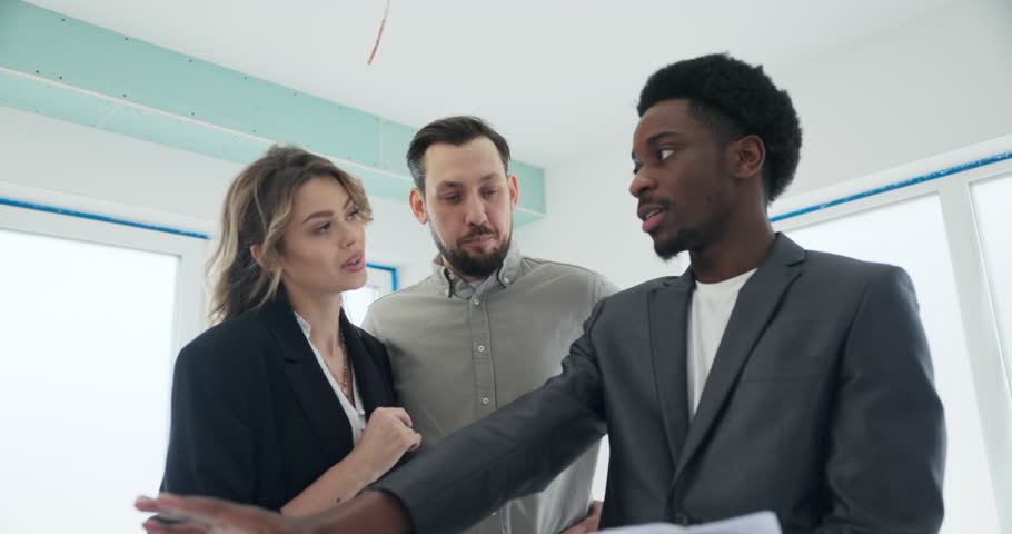 As the couple eagerly listens, the African real estate agent points out the intricate details on the plan, explaining how the untouched building can be customized to reflect their unique style.