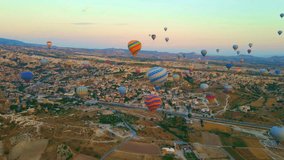 Aerial video. Captured against the canvas of the Cappadocian sky, this video showcases the enchanting spectacle of a hot air balloon festival. The vibrant balloons rise gracefully over the valleys of