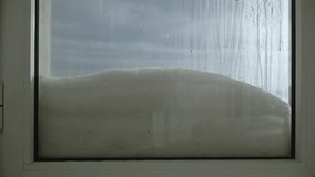 Drops from ice crust melting in sun from condensation flow down foggy snow-covered glass. Window with aluminum frame against background of blue sky after winter snowfall with slide of snow. - Powered by Shutterstock - Get 15% off with code: PIKWIZARD15