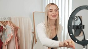 Young social medial content creator woman make fashion video. Blogger smiles to camera and light ring while making persuasive online clothing sell vlog to audience or follower. Blithe