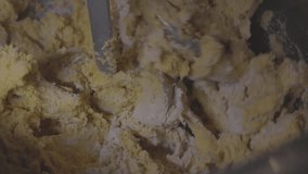 Mixing dough in electric mixer. Machine mixes pasta dough. Mixer kneading a dough, in slow motion video. Preparing dough in a restaurant. Slow motion 120 fps, ProRes 422, 10 bit, ungraded C-LOG video