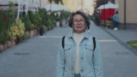 Outdoor portrait of happy elderly female having a good time during spring holidays. Positive cute senior woman cheerful smile on city background. Friendly grandmother wear denim shirt in her trip - Powered by Shutterstock - Get 15% off with code: PIKWIZARD15