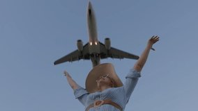 A joyful woman throws her arms up in excitement as a plane descends overhead - Powered by Shutterstock - Get 15% off with code: PIKWIZARD15
