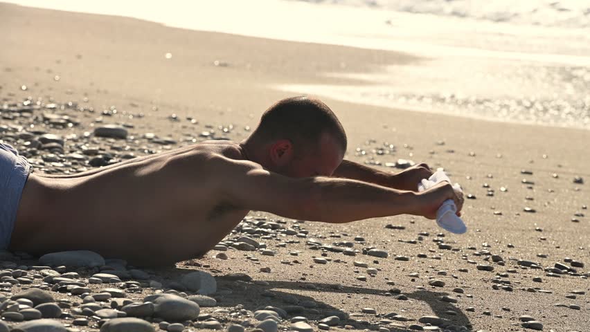 Young man doing abc exercise on the sandy beach in the morning