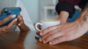 Barista hands putting cup delicious coffee on wooden table to woman client sitting with smartphone closeup. Unknown waiter bringing aromatic latte to african american girl. Young lady taking white mug - Powered by Shutterstock - Get 15% off with code: PIKWIZARD15