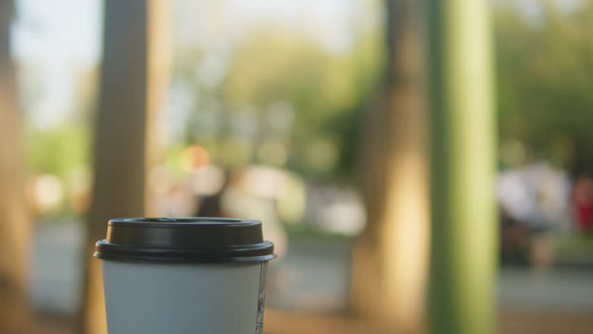 Cup of coffee to go nature backgroung close-up. Drink in carton cup on the table. Outdoors | Shutterstock HD Video #1112120559