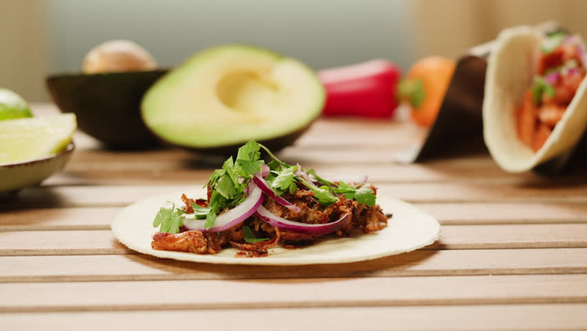 Traditional mexican food tacos with onion and cilantro on the top close-up. Squeezing lime on homemade tacos with meat and vegetables 