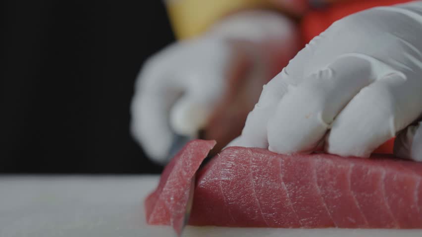 Female chef hand using fish fillet knife slice fresh tuna fish meat on cutting board in restaurant, Chef preparing healthy menu salmon sashimi or sushi to customer, Japanese cuisine recipes.